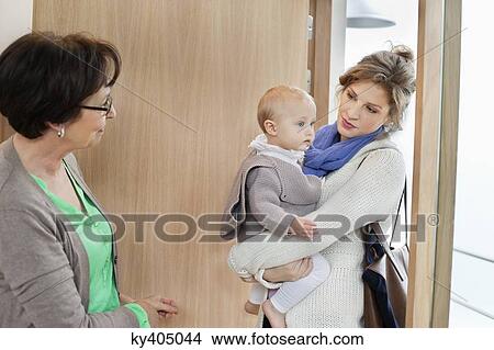 Woman with her daughter standing at the doorway View Large Photo Image Picture - Woman with her daughter standing at the doorway. Fotosearch