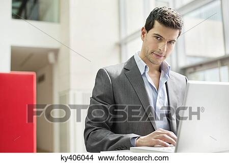 Businessman working on a laptop in an office View Large Photo Image Picture - Businessman working on a laptop in an office. Fotosearch