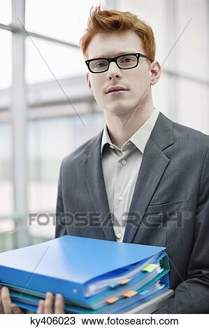 Portrait of a businessman holding files in an office View Large Photo Image Stock Image - Portrait of a businessman holding files in an office. Fotosearch