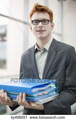 Portrait of a businessman holding files in an office View Large Photo Image Stock Image - Portrait of a businessman holding files in an office. Fotosearch
