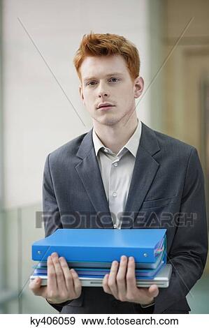 Portrait of a businessman holding files in an office View Large Photo Image Stock Photo - Portrait of a businessman holding files in an office. Fotosearch