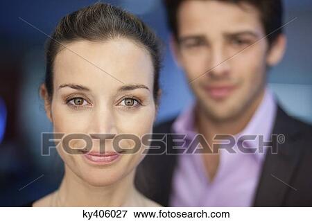 Stock Photo - Portrait of a businesswoman smiling with her colleague in the background. Fotosearch