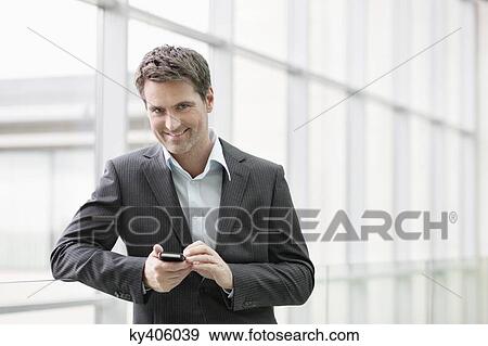 Stock Photo - Portrait of a businesswoman text messaging on a mobile phone in an office. Fotosearch
