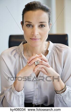 Portrait of a businesswoman with her hands clasped in an office View Large Photo Image Picture - Portrait of a businesswoman with her hands clasped in an office. Fotosearch