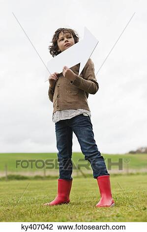Boy holding an arrow sign in a field View Large Photo Image Stock Image - Boy holding an arrow sign in a field. Fotosearch