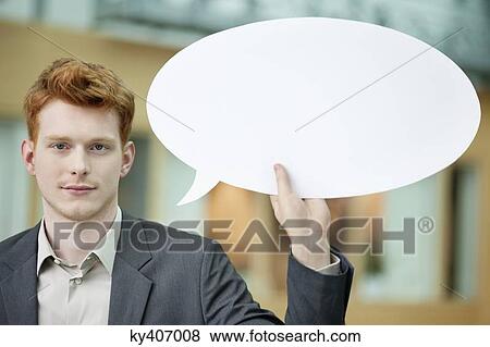 Businessman holding a speech bubble in an office View Large Photo Image Stock Photo - Businessman holding a speech bubble in an office. Fotosearch
