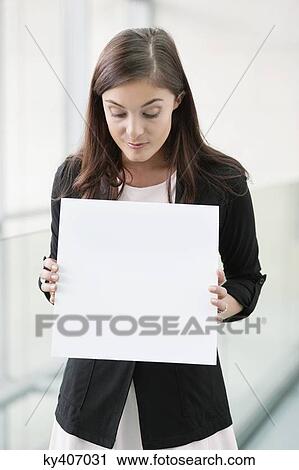 Businesswoman holding a blank placard in an office View Large Photo Image Stock Image - Businesswoman holding a blank placard in an office. Fotosearch