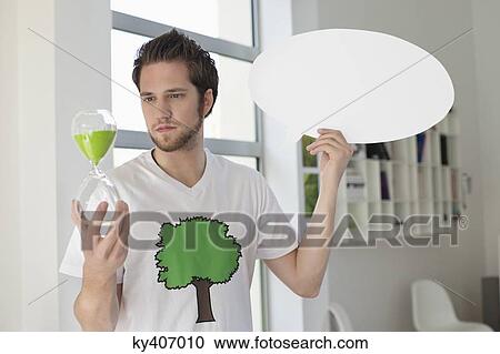Man holding an hour glass and a speech bubble View Large Photo Image Stock Image - Man holding an hour glass and a speech bubble. Fotosearch
