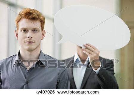 Portrait of a businessman with his colleague holding a speech bubble behind him View Large Photo Image Stock Photograph - Portrait of a businessman with his colleague holding a speech bubble behind him. Fotosearch
