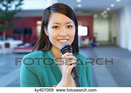 Portrait of a businesswoman holding microphone in an office View Large Photo Image Stock Photo - Portrait of a businesswoman holding microphone in an office. Fotosearch