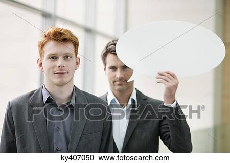Portrait of a businesswoman smiling with her colleague holding speech bubble behind her View Large Photo Image Stock Image - Portrait of a businesswoman smiling with her colleague holding speech bubble behind her. Fotosearch