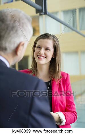 Stock Photo - Business executives discussing in an office corridor. Fotosearch