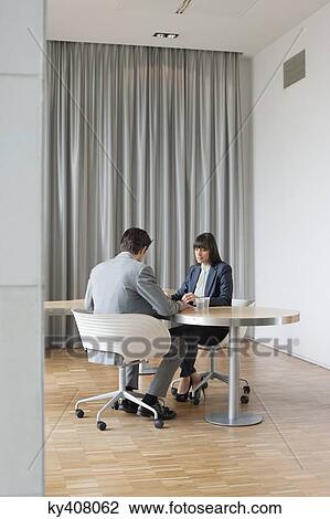 Stock Image - Business executives having a meeting in an office. Fotosearch