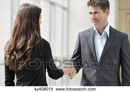 Stock Photography - Business executives shaking hands in an office. Fotosearch