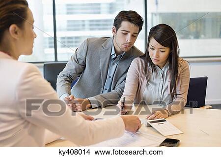 Couple signing documents with business executive View Large Photo Image Picture - Couple signing documents with business executive. Fotosearch