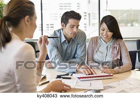 Stock Image - Real estate agent discussing property documents to his clients. Fotosearch