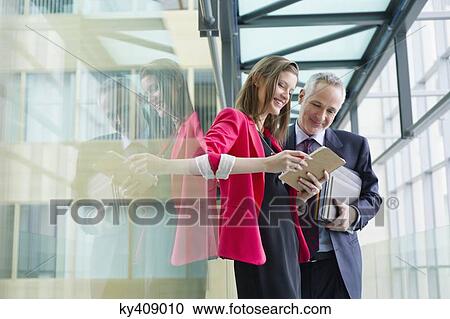 Business executives discussing in an office corridor View Large Photo Image Stock Image - Business executives discussing in an office corridor. Fotosearch