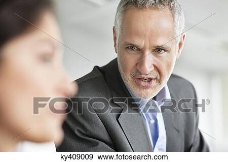 Stock Photo - Business executives discussing in an office. Fotosearch