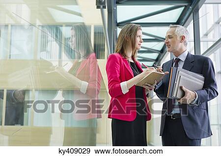 Stock Photo - Business executives discussing in an office corridor. Fotosearch