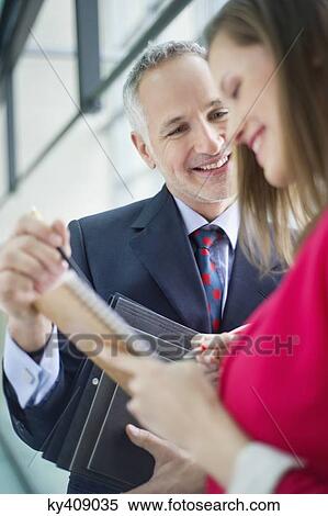 Stock Photography - Business executives discussing in an office corridor. Fotosearch