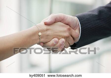 Stock Image - Close-up of business executives shaking hands in an office. Fotosearch