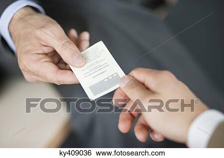 Stock Photograph - Close-up of Businessman giving card to another businessman. Fotosearch