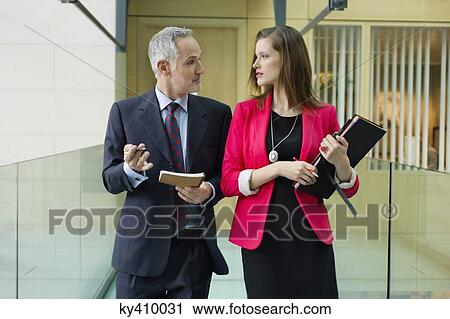 Business executives discussing in an office corridor View Large Photo Image Stock Image - Business executives discussing in an office corridor. Fotosearch