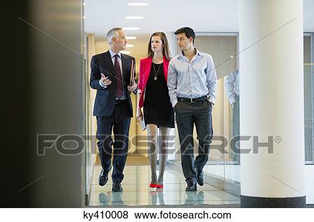 Business executives discussing in an office corridor View Large Photo Image Stock Photo - Business executives discussing in an office corridor. Fotosearch
