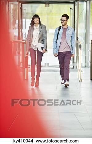Picture - Business executives entering in an office lobby. Fotosearch