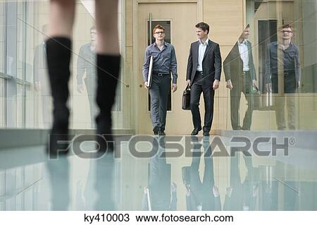 Stock Image - Business executives walking in a corridor. Fotosearch