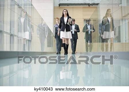 Stock Image - Business executives walking in a corridor. Fotosearch