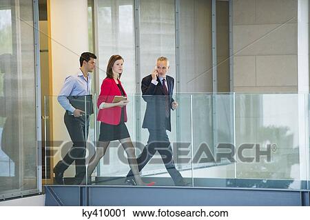 Stock Image - Business executives walking in an office corridor. Fotosearch