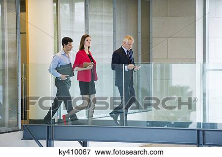 Stock Photo - Business executives walking in an office corridor. Fotosearch