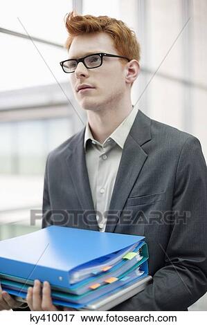 Businessman holding files in an office View Large Photo Image Stock Photo - Businessman holding files in an office. Fotosearch
