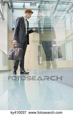 Businessman peeking through glass in a corridor View Large Photo Image Stock Photo - Businessman peeking through glass in a corridor. Fotosearch