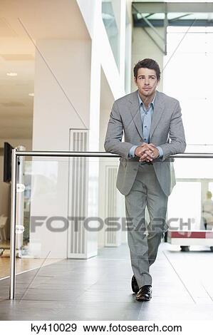 Businessman standing in an office corridor View Large Photo Image Stock Photo - Businessman standing in an office corridor. Fotosearch