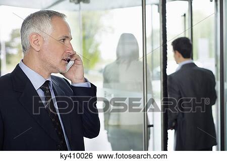 Businessman talking on a mobile phone in an office View Large Photo Image Stock Photograph - Businessman talking on a mobile phone in an office. Fotosearch