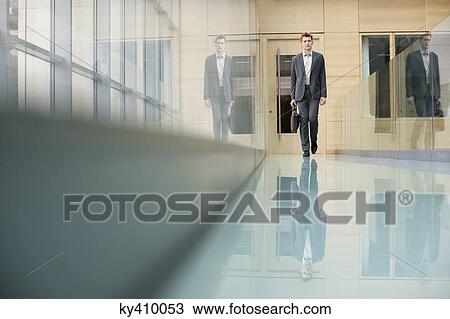 Businessman walking in an office corridor View Large Photo Image Stock Image - Businessman walking in an office corridor. Fotosearch