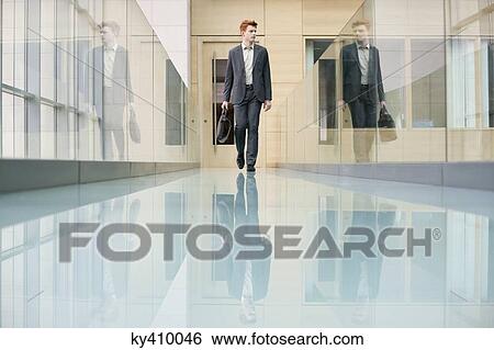 Stock Photograph - Businessman walking in an office corridor. Fotosearch