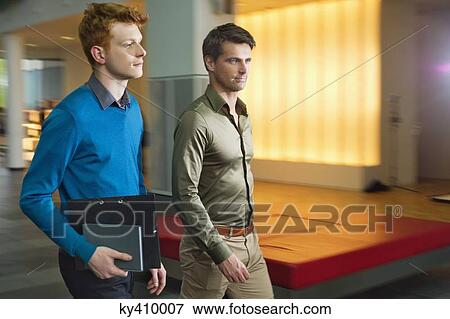 Stock Photo - Businessmen walking in an office corridor. Fotosearch