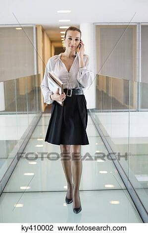 Businesswoman talking on a mobile phone in an office corridor View Large Photo Image Stock Image - Businesswoman talking on a mobile phone in an office corridor. Fotosearch