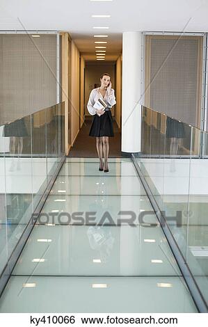 Businesswoman talking on a mobile phone in an office corridor View Large Photo Image Stock Photograph - Businesswoman talking on a mobile phone in an office corridor. Fotosearch