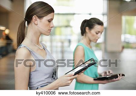 Businesswomen using digital tablets in an office View Large Photo Image Stock Photograph - Businesswomen using digital tablets in an office. Fotosearch