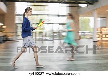 Businesswomen walking in an office lobby View Large Photo Image Stock Photo - Businesswomen walking in an office lobby. Fotosearch