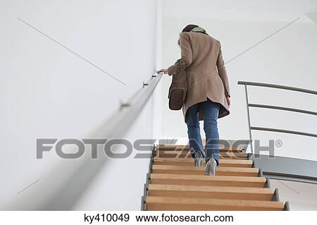 Rear view of a woman moving up staircase View Large Photo Image Stock Photo - Rear view of a woman moving up staircase. Fotosearch