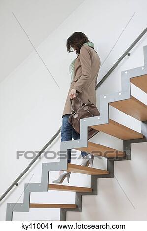 Stock Image - Woman moving down stairs. Fotosearch