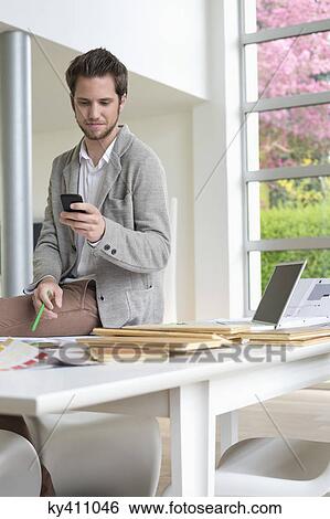 Interior designer using a mobile phone in the office View Large Photo Image Stock Photograph - Interior designer using a mobile phone in the office. Fotosearch