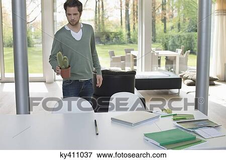 Stock Photo - Man holding a cactus plan. Fotosearch