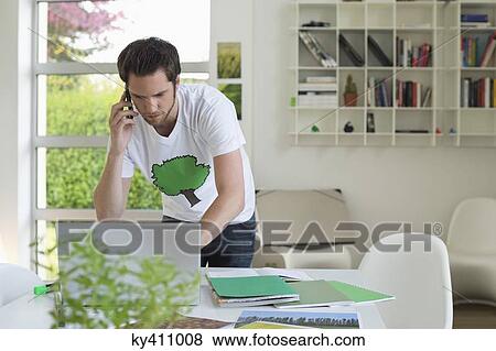 Man holding a mobile phone and working on a laptop View Large Photo Image Stock Photo - Man holding a mobile phone and working on a laptop. Fotosearch