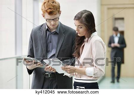 Stock Photography - Business executives using digital tablets in an office. Fotosearch